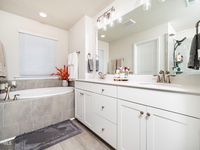 bathroom with tiled tub and vanity