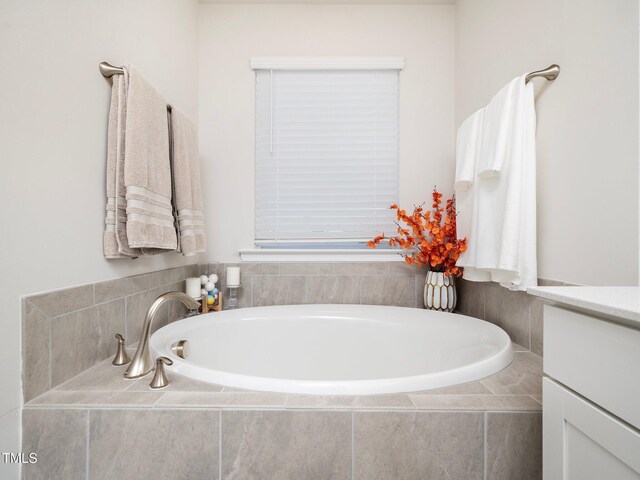 bathroom featuring vanity and tiled bath