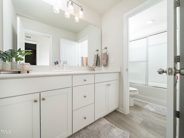 full bathroom featuring toilet, vanity, bath / shower combo with glass door, and hardwood / wood-style flooring