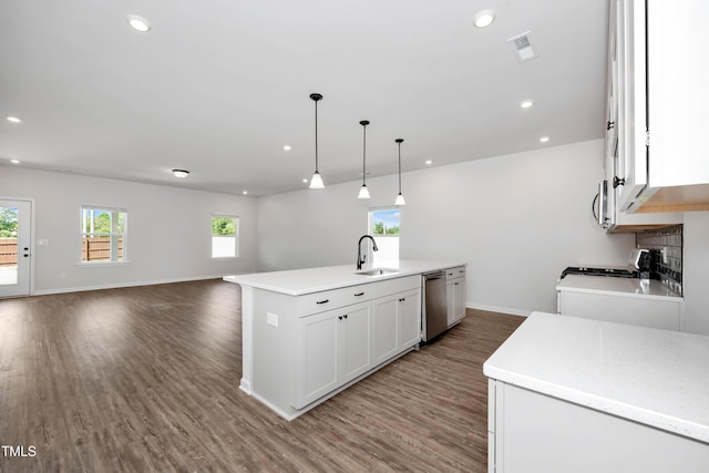 kitchen with sink, appliances with stainless steel finishes, an island with sink, white cabinets, and decorative light fixtures