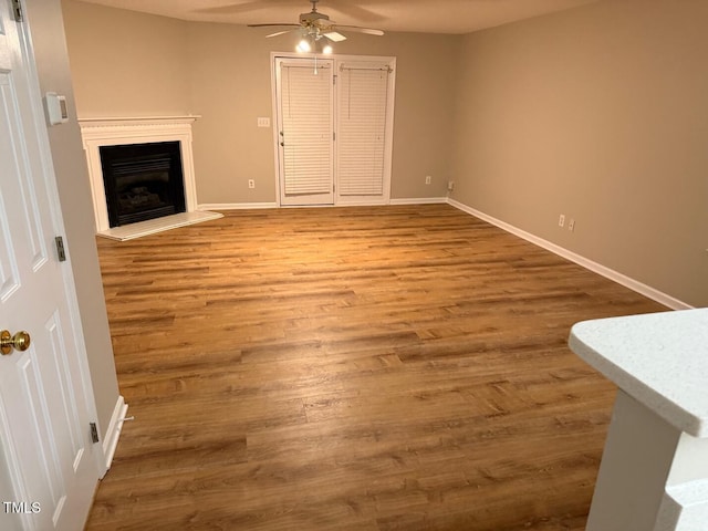 unfurnished living room featuring ceiling fan and hardwood / wood-style flooring