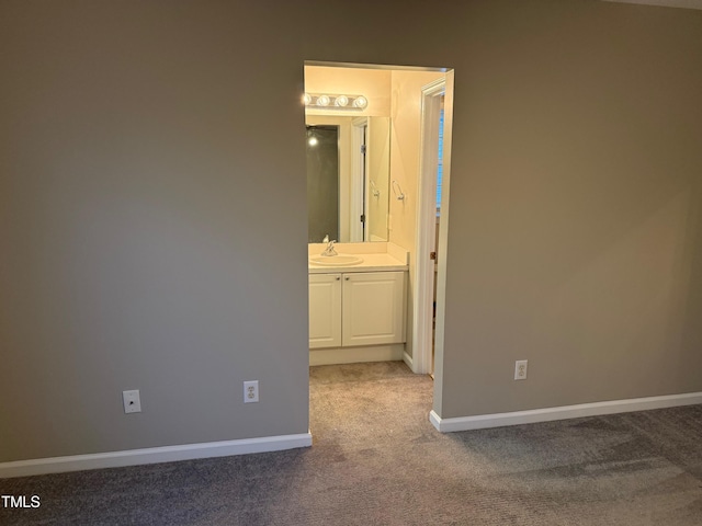 unfurnished bedroom featuring carpet floors, ensuite bathroom, and sink