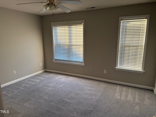 carpeted empty room with ceiling fan and plenty of natural light