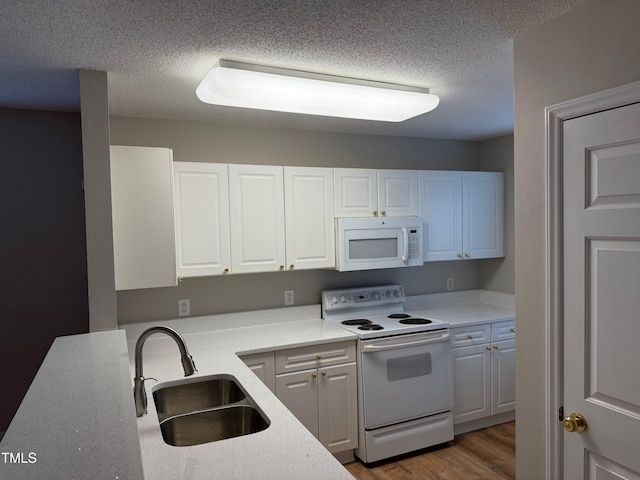 kitchen with white cabinetry, sink, a textured ceiling, white appliances, and light wood-type flooring