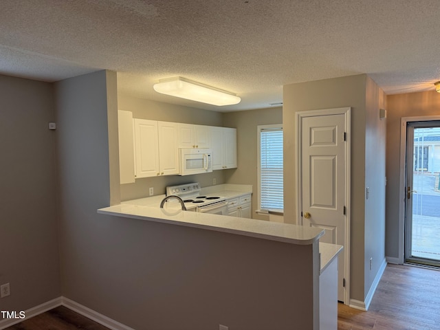 kitchen featuring kitchen peninsula, white appliances, hardwood / wood-style flooring, and white cabinetry