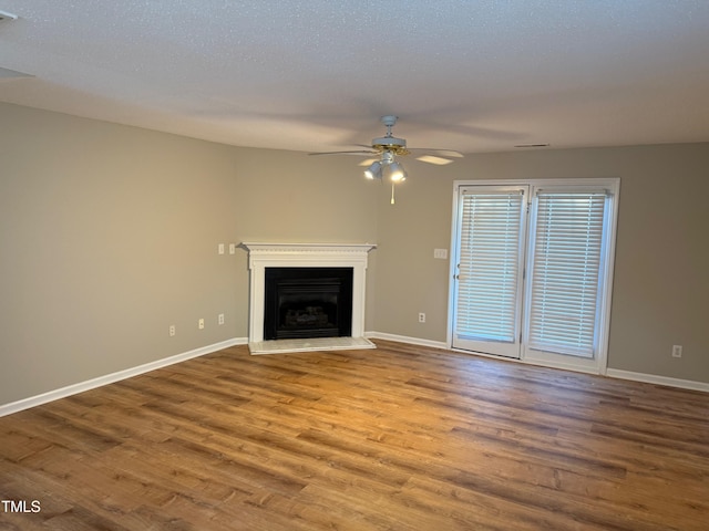 unfurnished living room featuring ceiling fan, wood-type flooring, and a textured ceiling