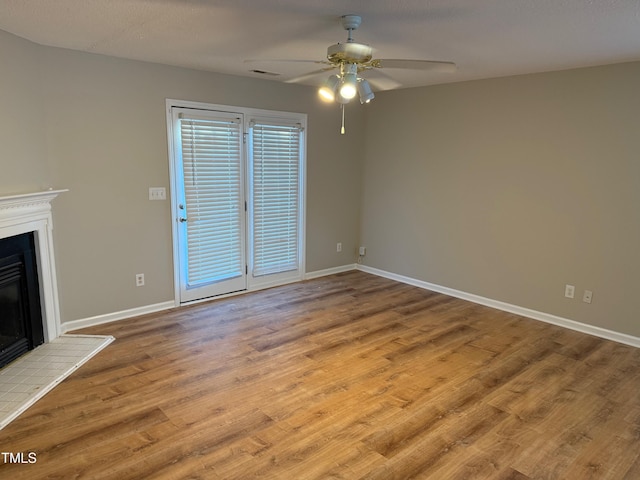 unfurnished living room featuring ceiling fan, light wood-type flooring, a textured ceiling, and a brick fireplace