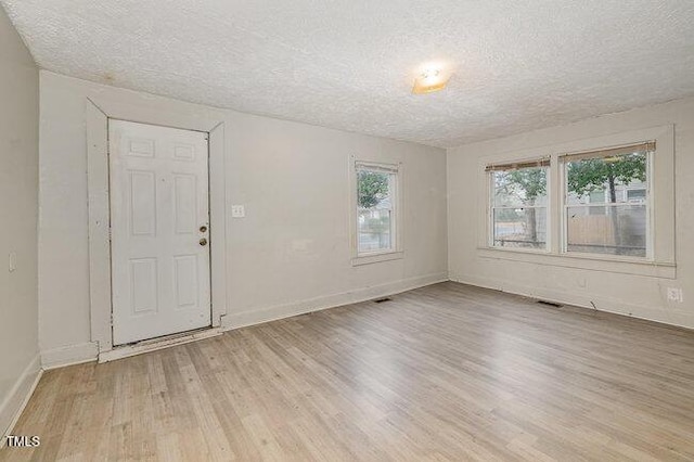 unfurnished room with light hardwood / wood-style floors and a textured ceiling