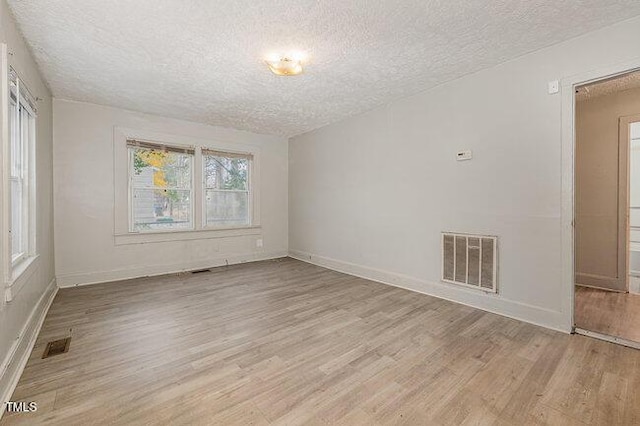 empty room featuring light wood-type flooring and a textured ceiling