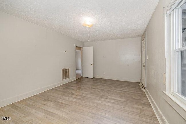 unfurnished room featuring light hardwood / wood-style floors and a textured ceiling