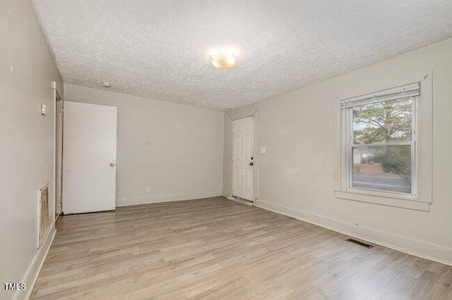 empty room with a textured ceiling and light wood-type flooring