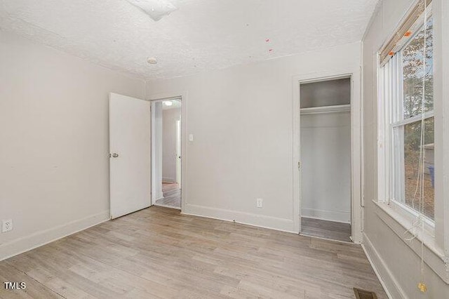 unfurnished bedroom featuring a closet, a textured ceiling, and light wood-type flooring