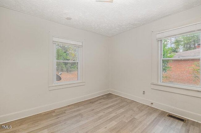 unfurnished room featuring light hardwood / wood-style floors and a textured ceiling