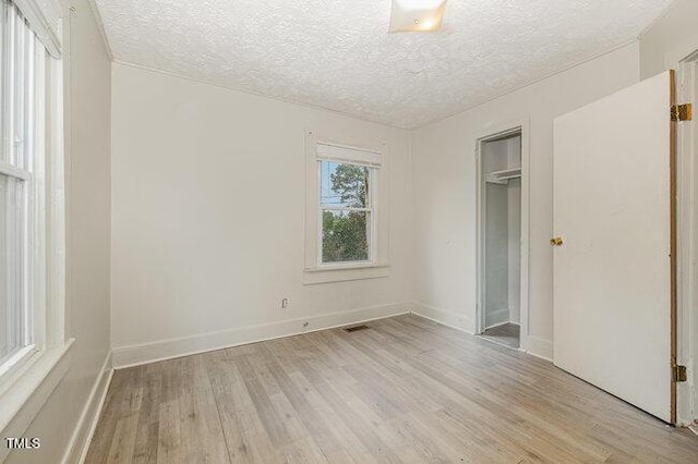 unfurnished bedroom with a closet, a textured ceiling, and light wood-type flooring