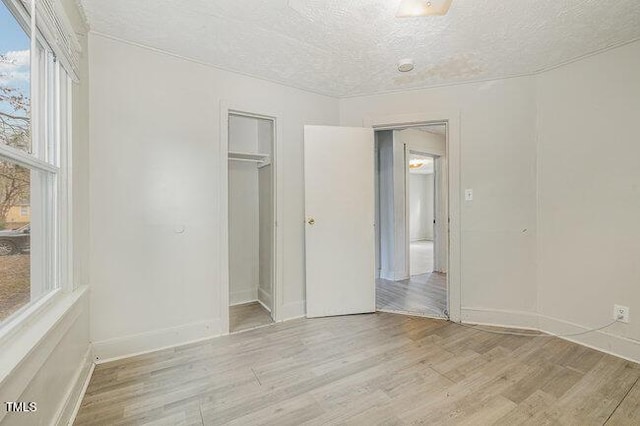 unfurnished bedroom featuring a closet, light hardwood / wood-style flooring, and a textured ceiling