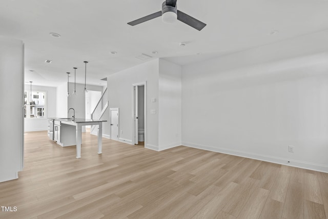 spare room featuring ceiling fan, sink, and light wood-type flooring