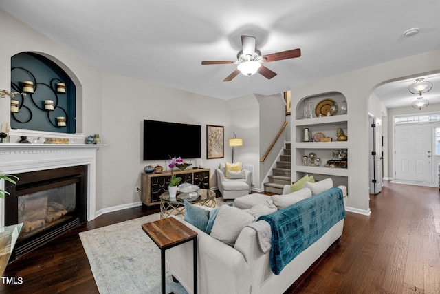 living room with dark hardwood / wood-style flooring, built in features, and ceiling fan