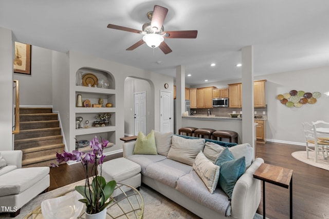 living room with dark hardwood / wood-style flooring, ceiling fan, and built in features