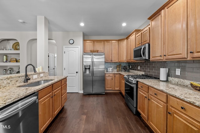 kitchen with stainless steel appliances, light stone counters, dark wood-type flooring, and sink