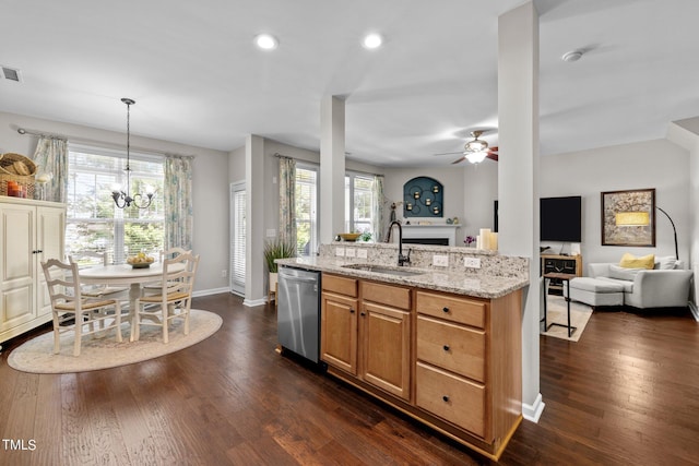 kitchen featuring light stone counters, a wealth of natural light, sink, pendant lighting, and dishwasher