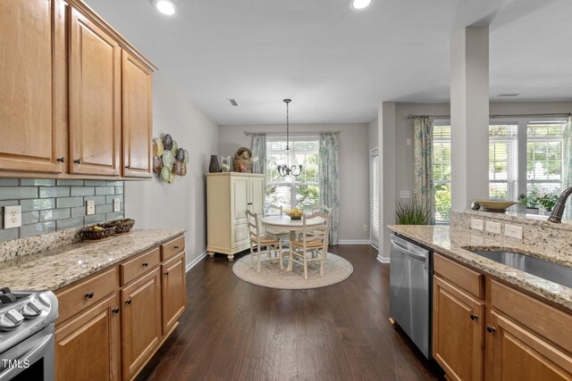 kitchen featuring appliances with stainless steel finishes, backsplash, sink, pendant lighting, and a notable chandelier