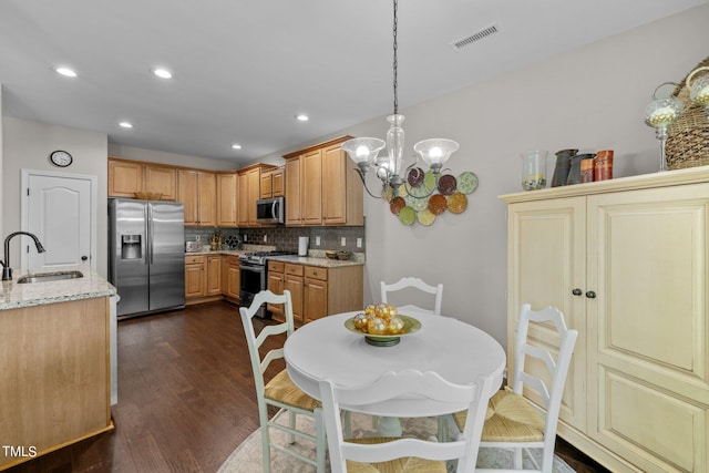 kitchen featuring pendant lighting, sink, decorative backsplash, light stone countertops, and stainless steel appliances