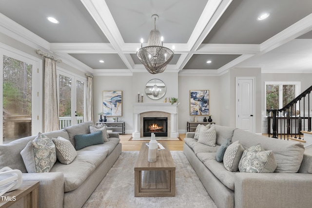 living room with beam ceiling, a notable chandelier, light hardwood / wood-style flooring, crown molding, and coffered ceiling