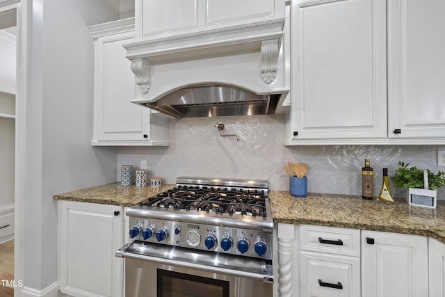 kitchen featuring white cabinets, stainless steel range, dark stone counters, and custom range hood