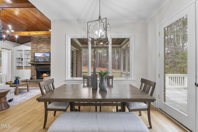 dining area featuring a chandelier, light hardwood / wood-style floors, a fireplace, and built in shelves