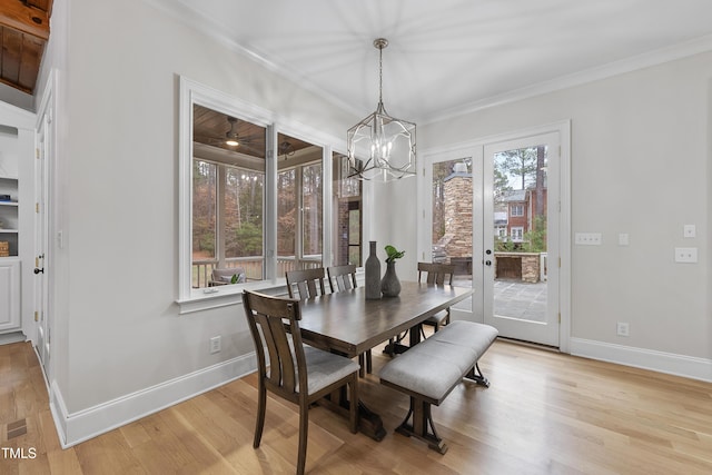 dining area featuring french doors, a notable chandelier, crown molding, and light hardwood / wood-style flooring