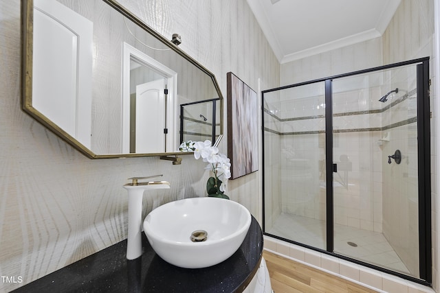 bathroom featuring ornamental molding, a shower with shower door, hardwood / wood-style floors, and sink