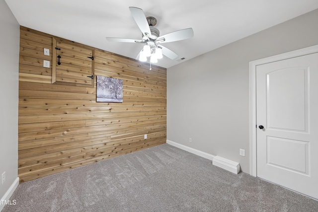 empty room featuring carpet, ceiling fan, and wooden walls