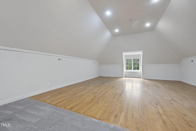 additional living space featuring vaulted ceiling and light wood-type flooring