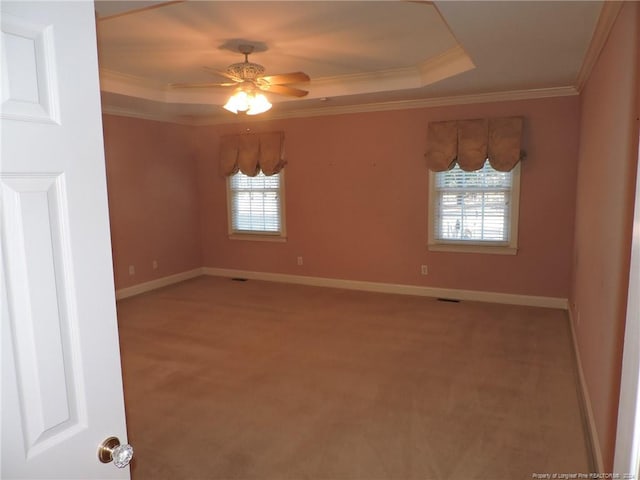 unfurnished room featuring carpet floors, a raised ceiling, ceiling fan, and ornamental molding