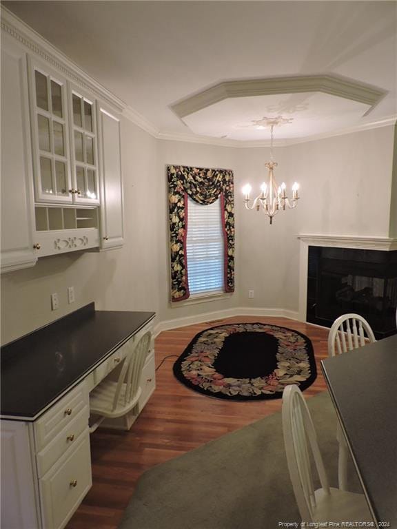 dining space with a notable chandelier, crown molding, and dark wood-type flooring