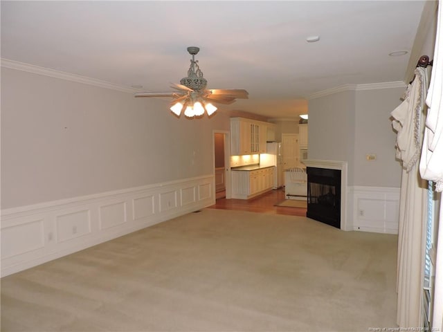 unfurnished living room with ceiling fan, light colored carpet, and ornamental molding