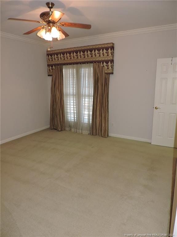 carpeted spare room with crown molding and ceiling fan