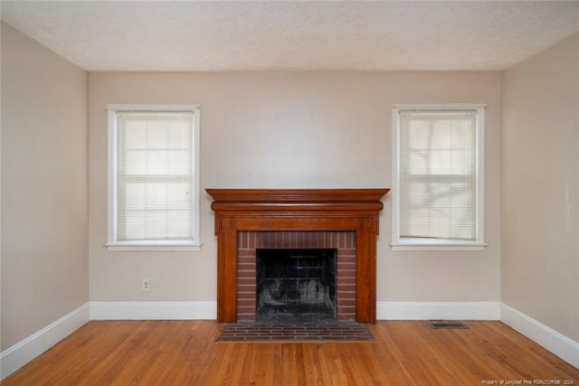 unfurnished living room featuring a wealth of natural light, a fireplace, and light hardwood / wood-style floors