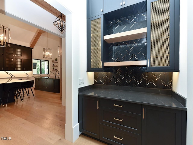 bar featuring decorative backsplash, pendant lighting, a notable chandelier, vaulted ceiling with beams, and light hardwood / wood-style floors