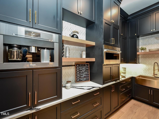 kitchen featuring sink, backsplash, light hardwood / wood-style floors, and stainless steel oven