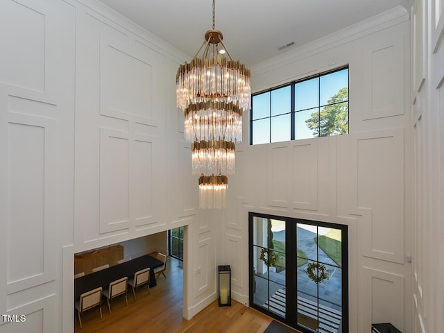 entryway with a notable chandelier, light hardwood / wood-style floors, and ornamental molding