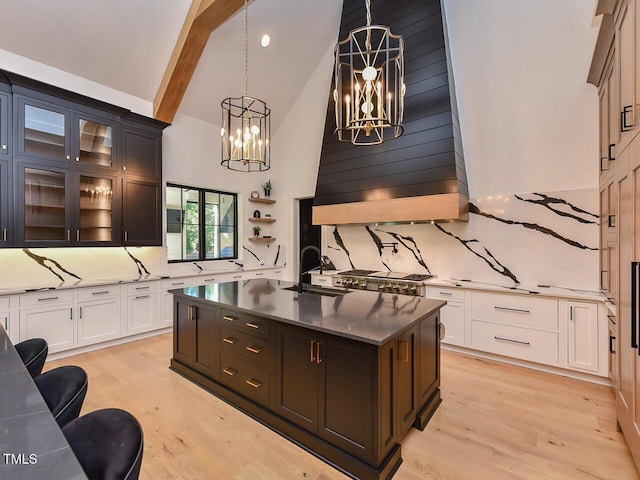 kitchen featuring tasteful backsplash, sink, pendant lighting, a center island with sink, and white cabinetry