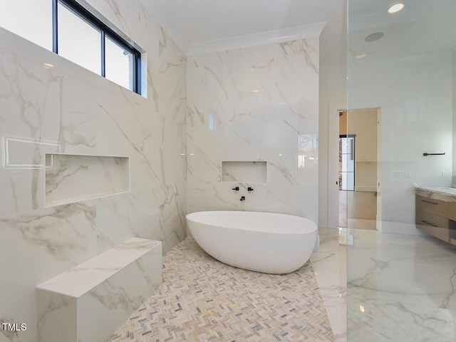 bathroom with vanity, a bath, and tile walls