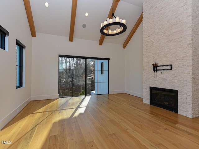 unfurnished living room featuring hardwood / wood-style flooring, beam ceiling, a healthy amount of sunlight, and a fireplace