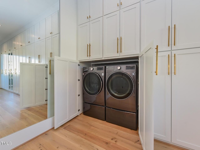 laundry area with cabinets, light wood-type flooring, and washing machine and clothes dryer