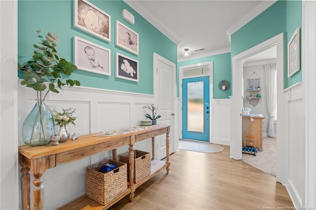 entryway featuring ornamental molding and light hardwood / wood-style flooring