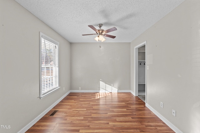 spare room featuring ceiling fan, light hardwood / wood-style floors, and a textured ceiling