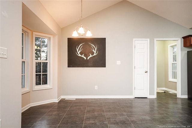 tiled empty room with vaulted ceiling and a notable chandelier