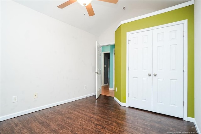 unfurnished bedroom featuring dark hardwood / wood-style flooring, lofted ceiling, ceiling fan, and a closet