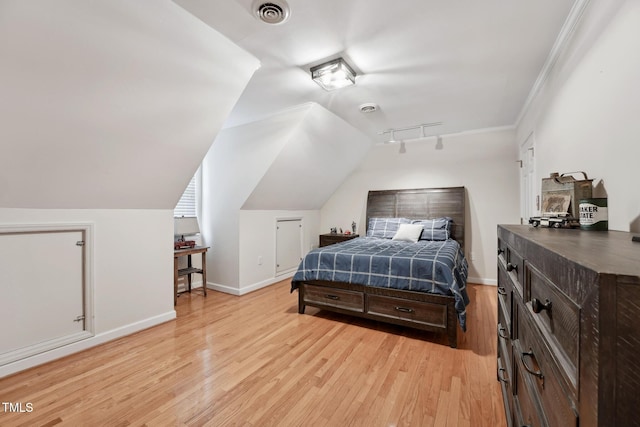 bedroom with light hardwood / wood-style floors, vaulted ceiling, and ornamental molding